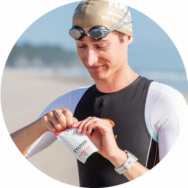 Triathlete eats Roam Energy Nut Butter on beach after swimming